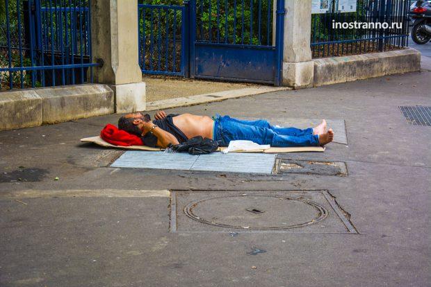 Бомж клошара спит на улице в Париже